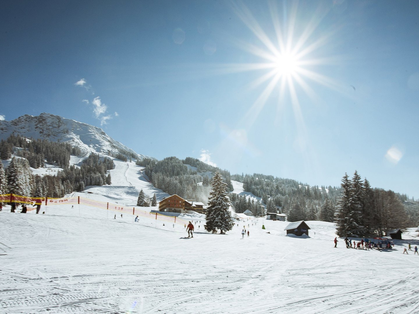 Skifahren lernen im Herzen des Allgäus Sonniger Skitag auf schneebedecktem Berg mit Skifahrern und Hütten