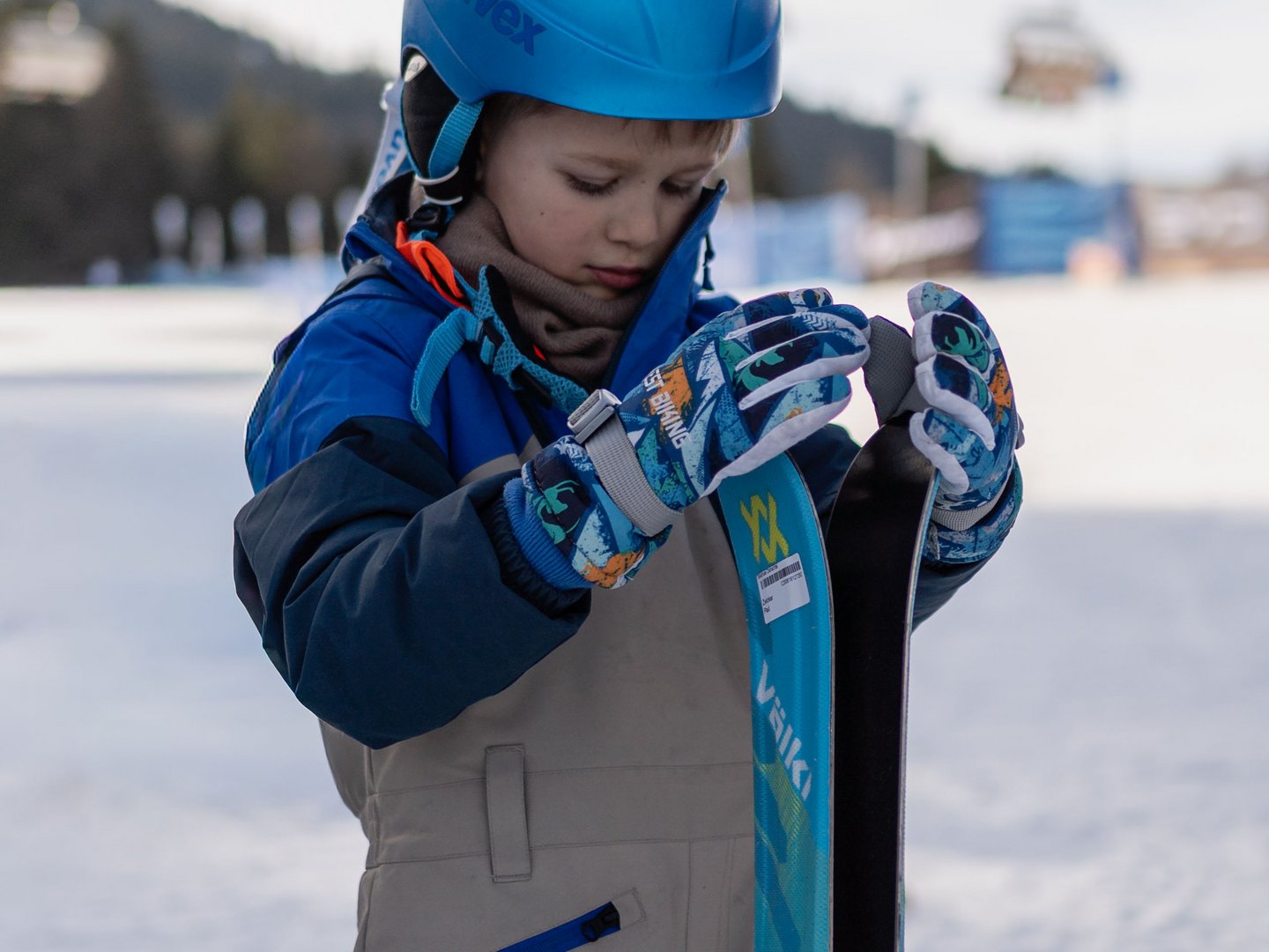 Skifahren lernen im Herzen des Allgäus Kind mit blauem Helm hält auf einer verschneiten Piste zwei Skier fest