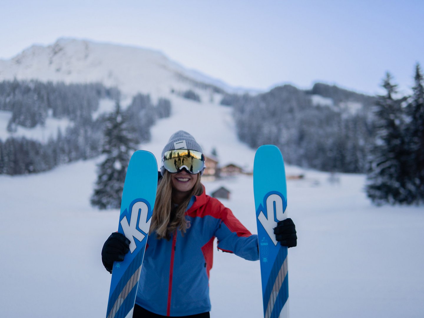 Skifahren lernen im Herzen des Allgäus Skifahrerin hält ihre Skier vor einer verschneiten Berglandschaft