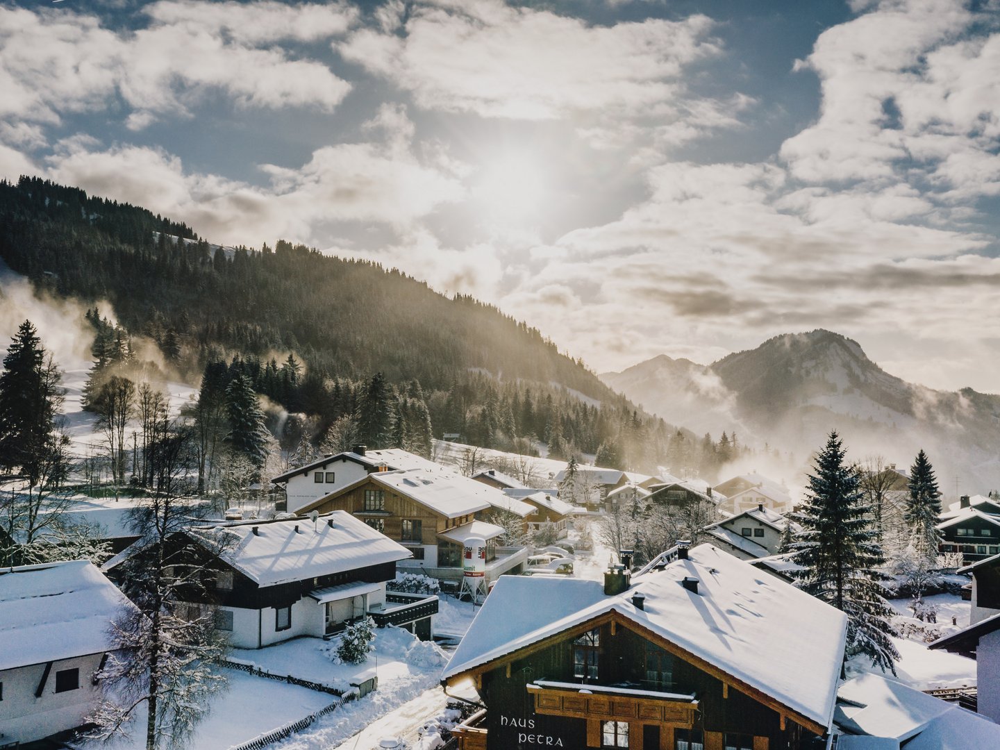 Skifahren lernen im Herzen des Allgäus Winterlandschaft mit schneebedeckten Häusern und Bergen im Hintergrund